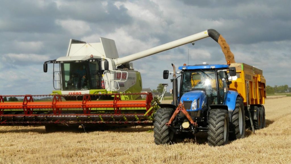 Combine harvester filling a trailer during harvest in Northern Ireland